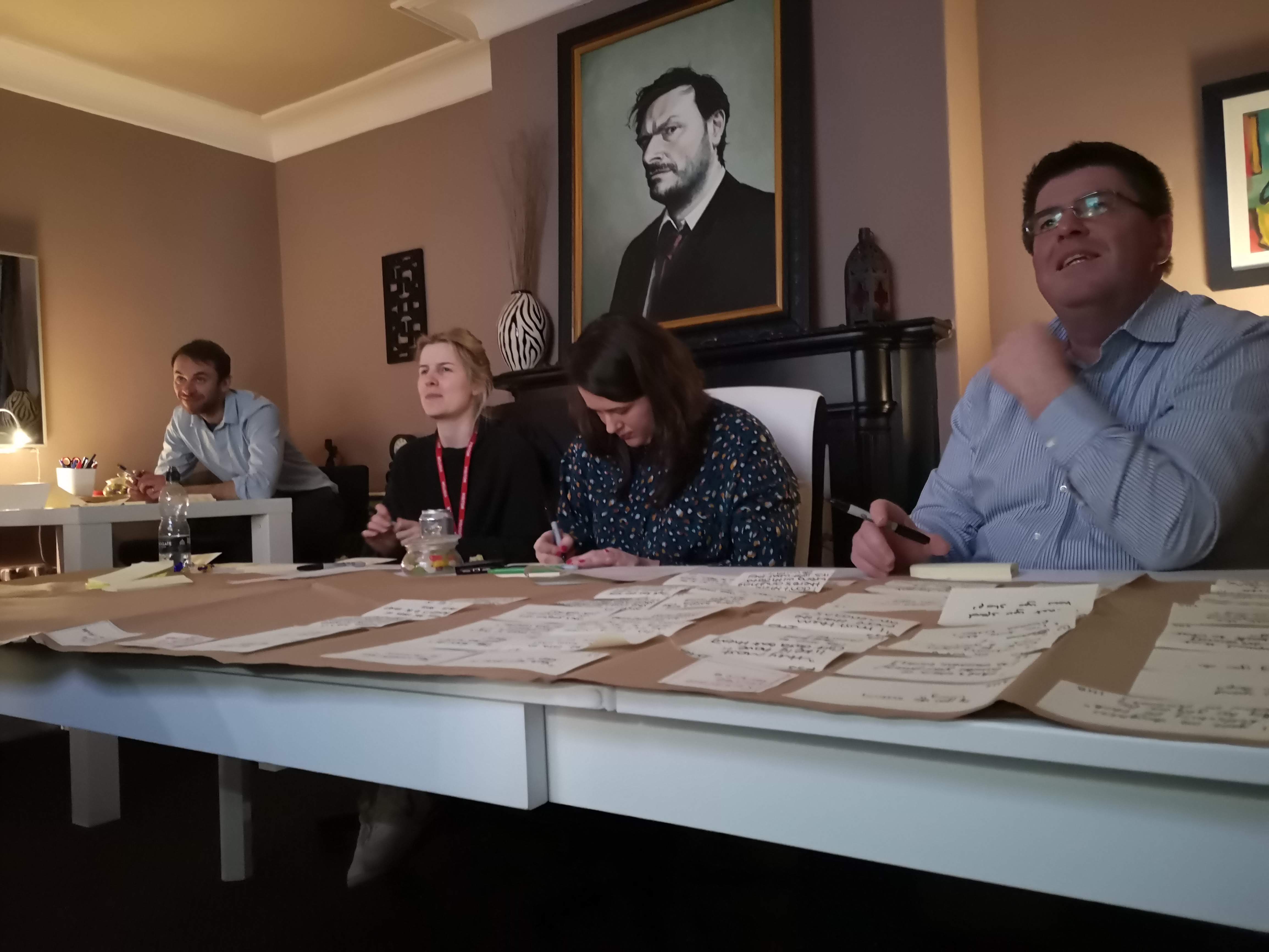 Several people sitting at a desk writing up notes